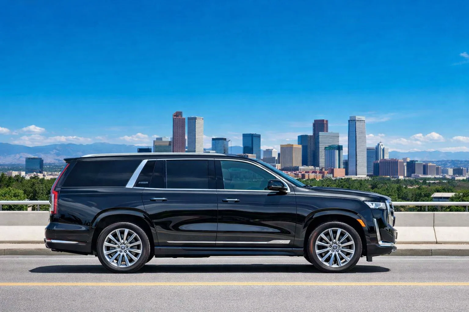 Black Cadillac Escalade with the downtown Denver skyline and Rocky Mountains behind it